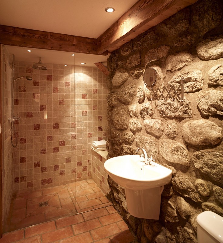 Bathroom with walk in shower and exposed granite wall